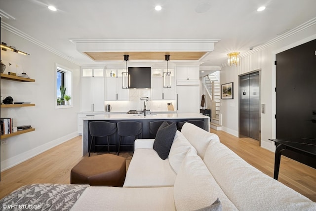 living room featuring stairway, ornamental molding, elevator, and light wood finished floors