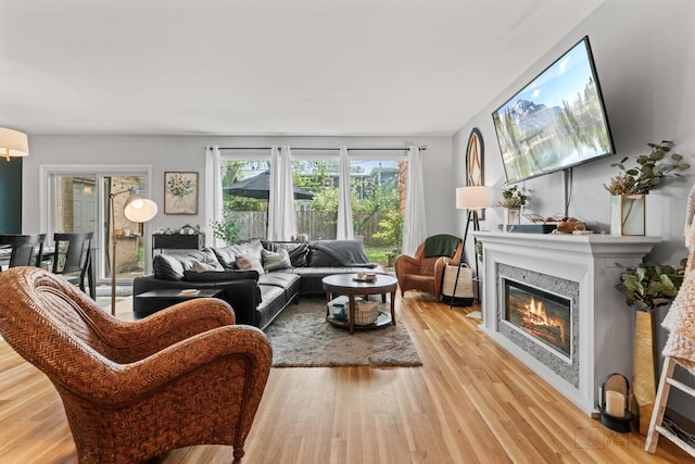 living area with light wood-style flooring and a glass covered fireplace