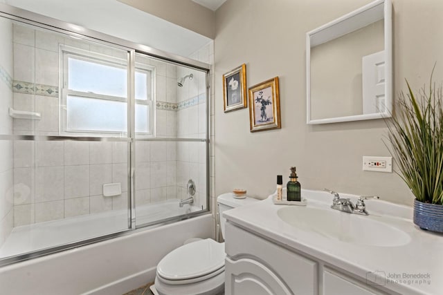 bathroom featuring toilet, vanity, and shower / bath combination with glass door