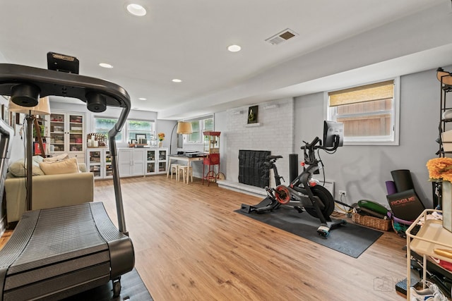 workout room featuring a fireplace, wood finished floors, and recessed lighting