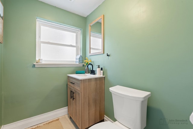 bathroom featuring toilet, vanity, and baseboards