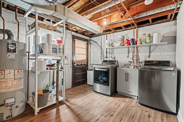 unfinished basement featuring gas water heater, washing machine and clothes dryer, light wood-type flooring, and concrete block wall