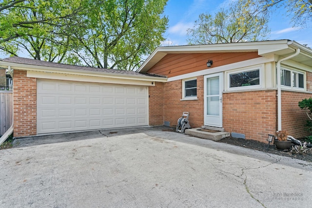 view of front of property featuring brick siding, driveway, and a garage