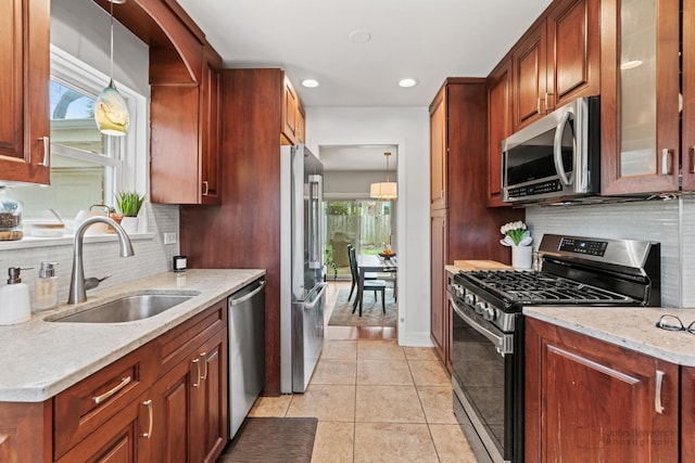 kitchen featuring stainless steel appliances, a sink, decorative backsplash, light stone countertops, and recessed lighting