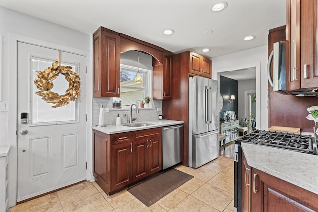 kitchen featuring a sink, stainless steel appliances, tasteful backsplash, light tile patterned floors, and light stone counters