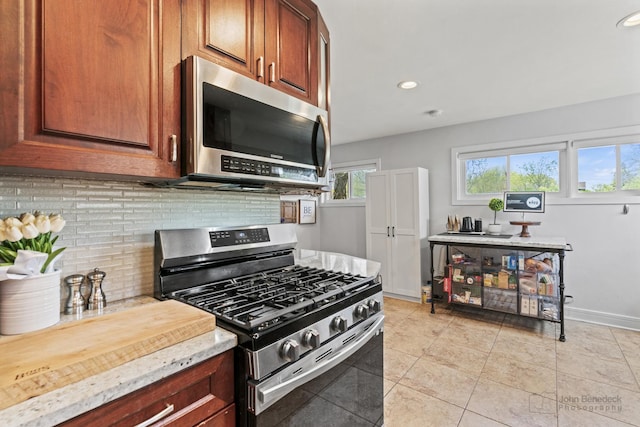 kitchen featuring stainless steel appliances, tasteful backsplash, light tile patterned floors, recessed lighting, and light stone counters