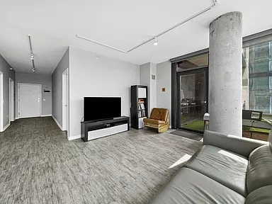 living area featuring baseboards, wood finished floors, attic access, and track lighting