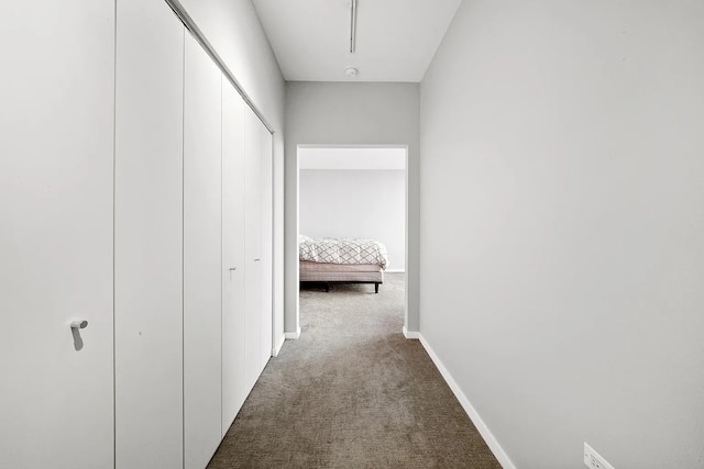 hallway featuring carpet and baseboards
