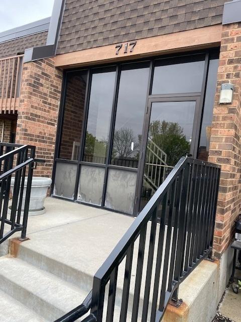 property entrance featuring brick siding and roof with shingles
