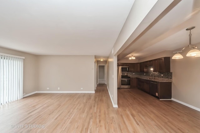 unfurnished living room featuring baseboards, a sink, and light wood-type flooring