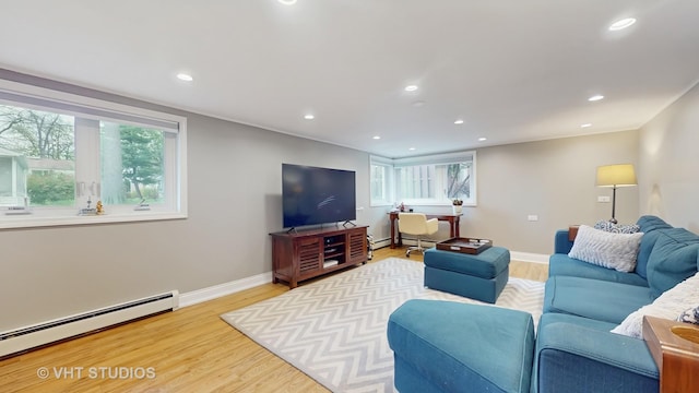 living room with a baseboard heating unit, plenty of natural light, and light wood-type flooring