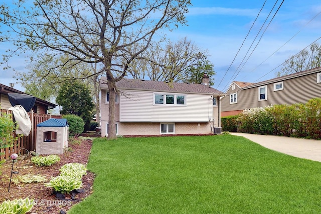 back of property with a lawn, central AC, fence, and a chimney