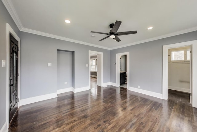 unfurnished bedroom with a spacious closet, crown molding, baseboards, dark wood-style flooring, and a closet