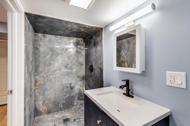 bathroom with a tile shower and vanity