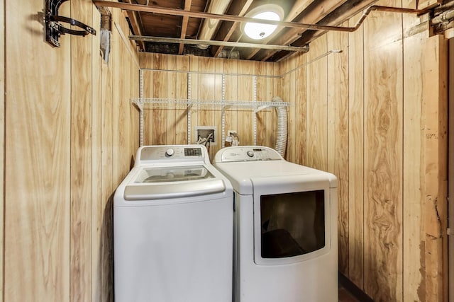 clothes washing area featuring washing machine and clothes dryer and wood walls