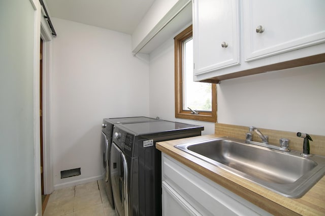 laundry area featuring cabinet space, a sink, baseboards, light tile patterned floors, and washer and clothes dryer