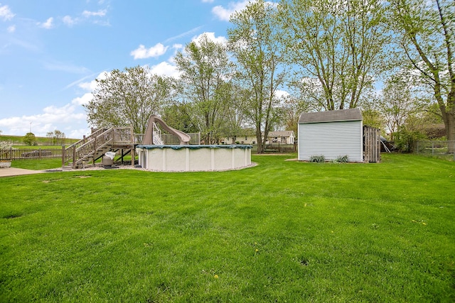 view of yard featuring a fenced backyard, a shed, a covered pool, stairs, and an outbuilding