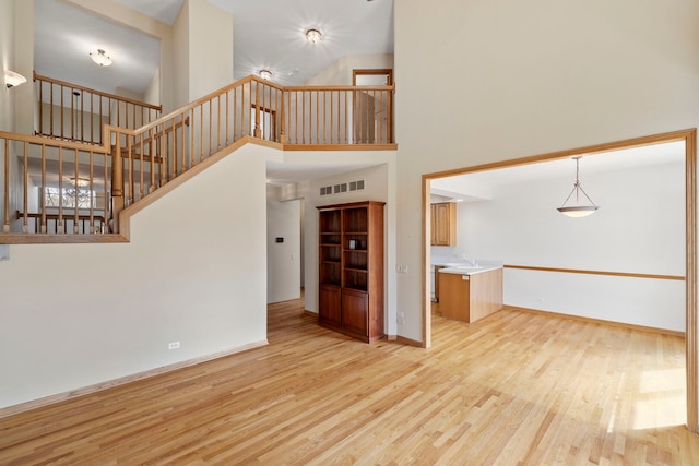 unfurnished living room featuring stairway, baseboards, wood finished floors, and visible vents