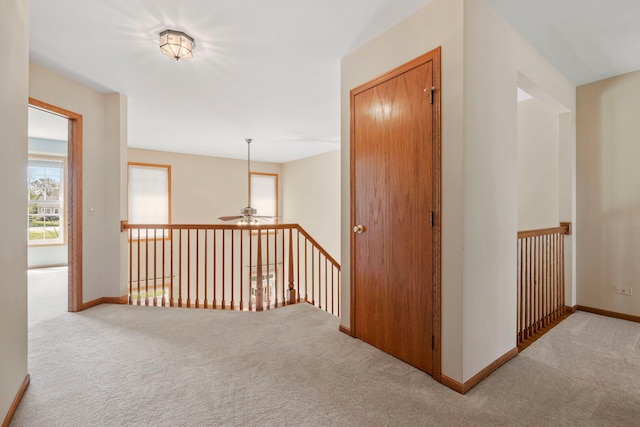 corridor with carpet floors, baseboards, and an upstairs landing
