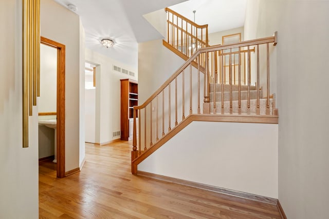 stairway with baseboards, wood finished floors, and visible vents