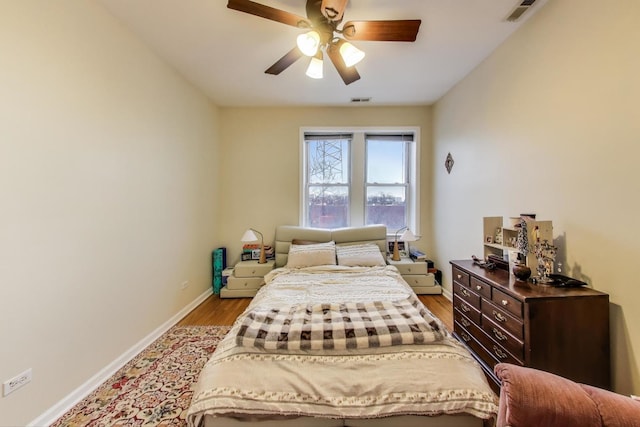 bedroom featuring wood finished floors, visible vents, ceiling fan, and baseboards