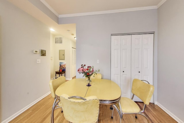 dining space featuring baseboards, visible vents, light wood-type flooring, and crown molding