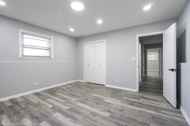 unfurnished bedroom with recessed lighting, multiple windows, and wood finished floors