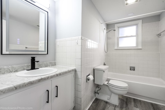 bathroom with visible vents, vanity, wood finished floors, toilet, and tile walls