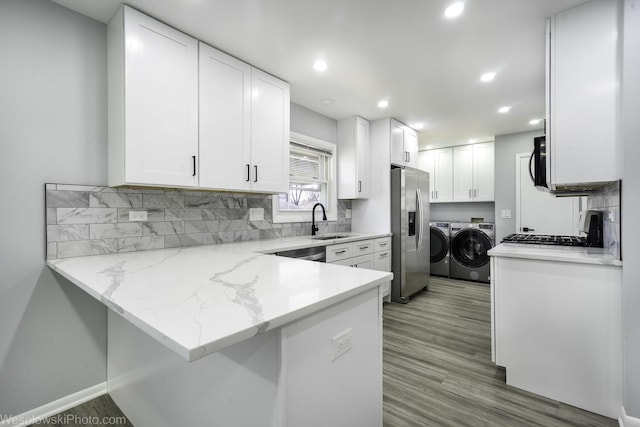 kitchen with a sink, appliances with stainless steel finishes, white cabinets, and independent washer and dryer