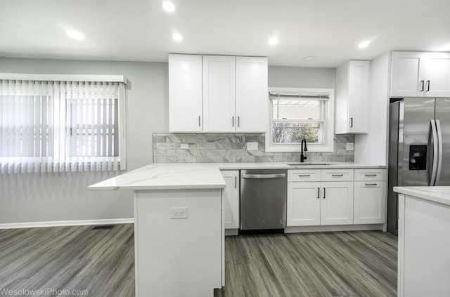kitchen with a sink, wood finished floors, white cabinets, and stainless steel appliances