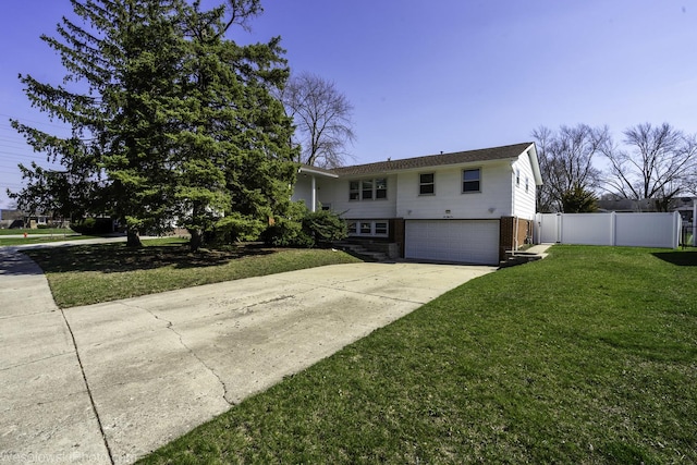 bi-level home with driveway, a front yard, a garage, brick siding, and fence