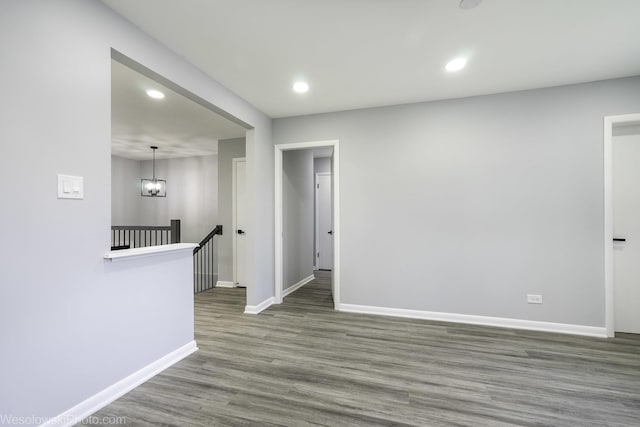 unfurnished room with baseboards, recessed lighting, wood finished floors, and a notable chandelier