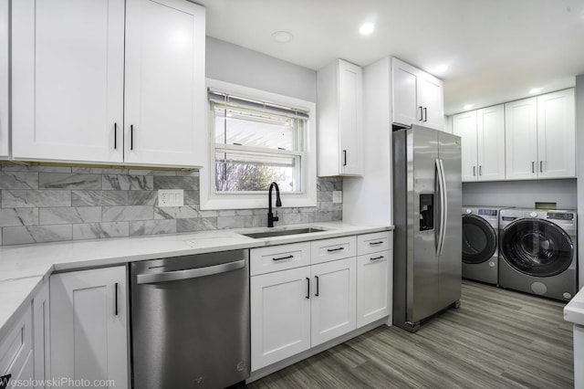 kitchen featuring a sink, white cabinetry, washer and dryer, and stainless steel appliances