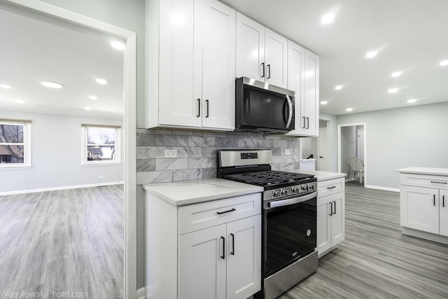 kitchen featuring baseboards, light wood-style floors, tasteful backsplash, and stainless steel appliances