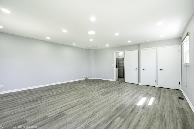 unfurnished bedroom featuring visible vents, freestanding refrigerator, wood finished floors, baseboards, and recessed lighting
