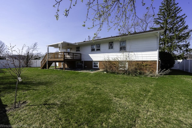 rear view of property with a deck, a fenced backyard, stairs, brick siding, and a lawn