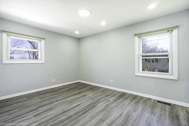 empty room with baseboards, recessed lighting, wood finished floors, and visible vents