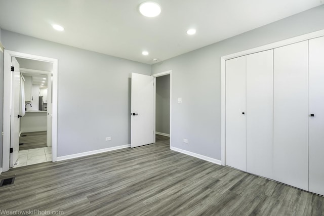 unfurnished bedroom featuring visible vents, wood finished floors, baseboards, a closet, and recessed lighting