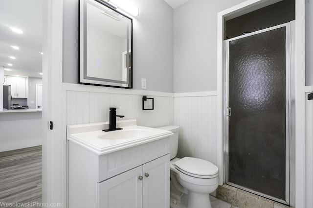bathroom featuring vanity, a shower stall, wainscoting, and toilet