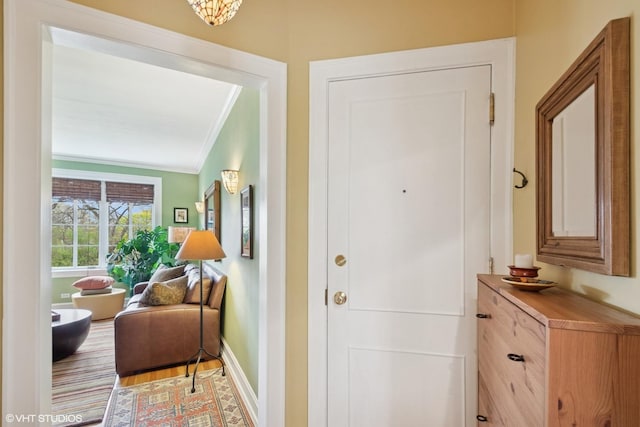 entrance foyer featuring crown molding, baseboards, and light wood finished floors