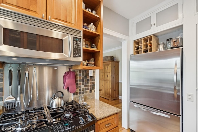 kitchen featuring appliances with stainless steel finishes, open shelves, tasteful backsplash, light stone countertops, and ornamental molding