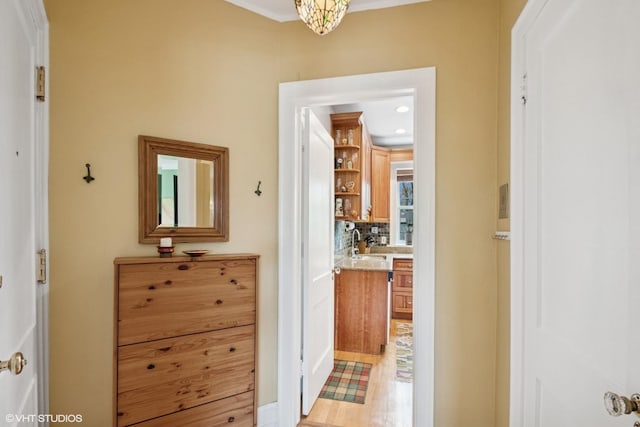 corridor featuring a sink and light wood finished floors