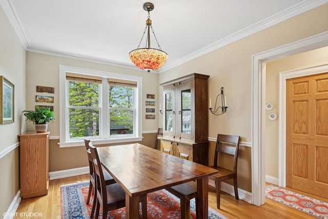 dining room with healthy amount of natural light, light wood-style floors, ornamental molding, and baseboards