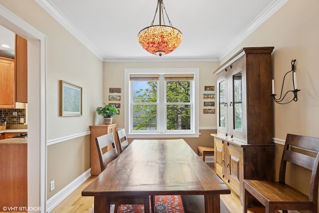 dining room featuring ornamental molding, baseboards, a chandelier, and light wood-type flooring