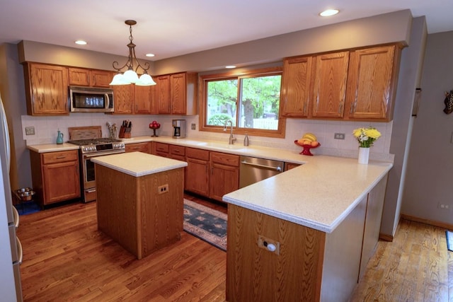 600 Salceda Dr, Mundelein, IL 60060 - kitchen with appliances with stainless steel finishes, a sink, light wood finished floors, brown cabinets, and a peninsula