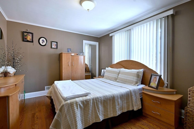bedroom with dark wood-type flooring, ornamental molding, and baseboards
