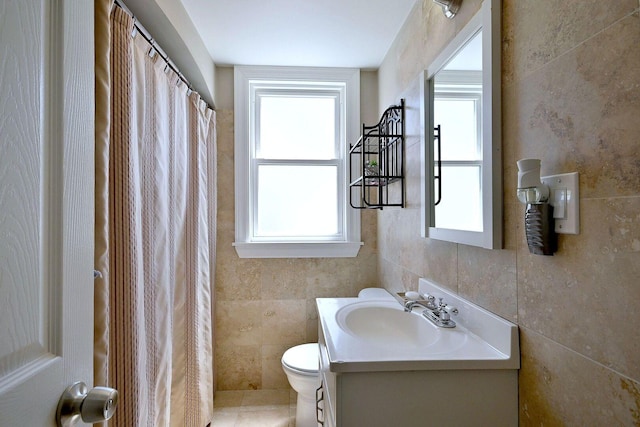 bathroom with vanity, toilet, tile walls, and curtained shower