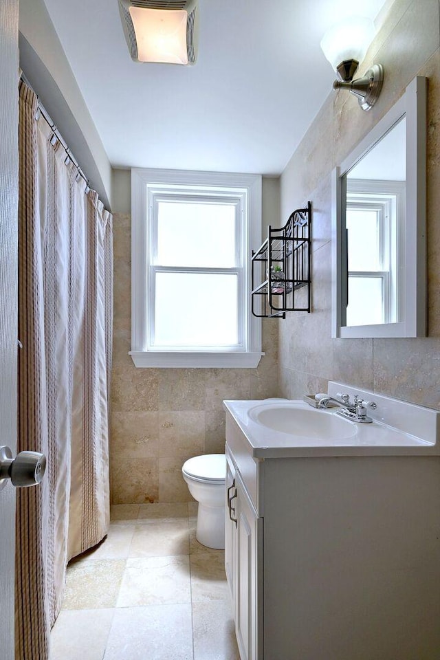 bathroom with tile walls, vanity, toilet, and curtained shower