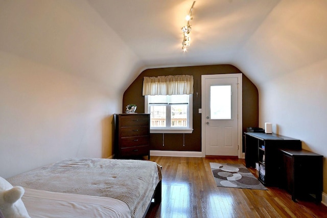 bedroom with wood-type flooring, lofted ceiling, and baseboards
