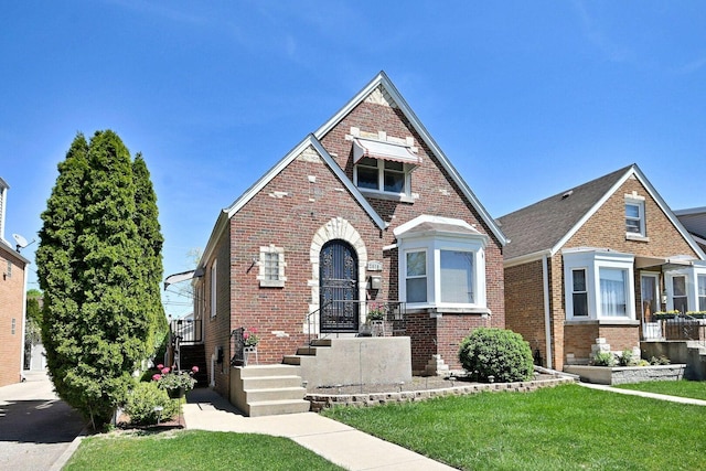 tudor home featuring brick siding and a front yard